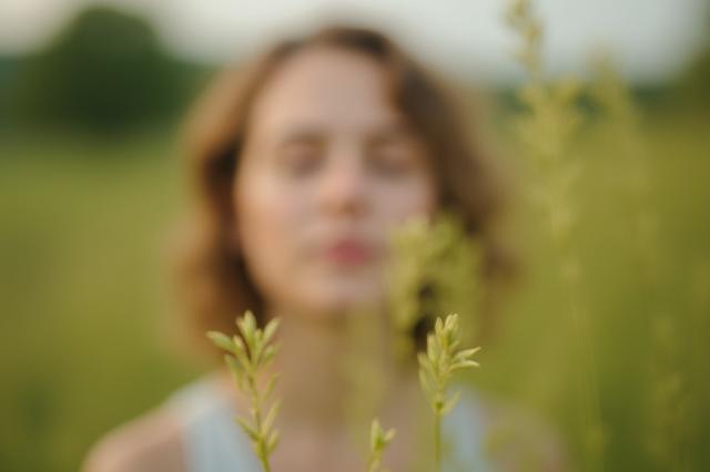 A person practicing deep breathing exercises outdoors, surrounded by nature, for stress reduction.